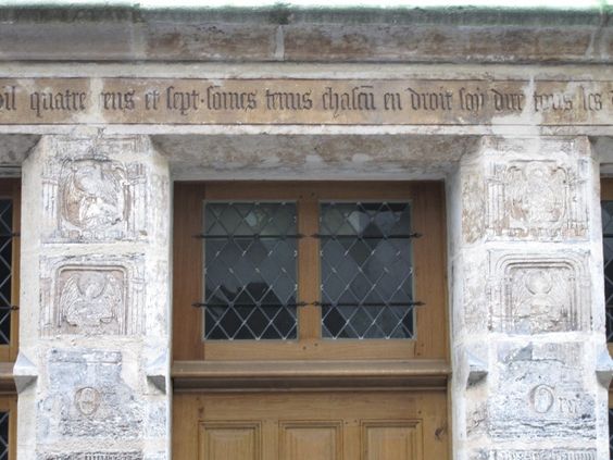 The inscription above the door at Flamel's house, flanked by musician angels